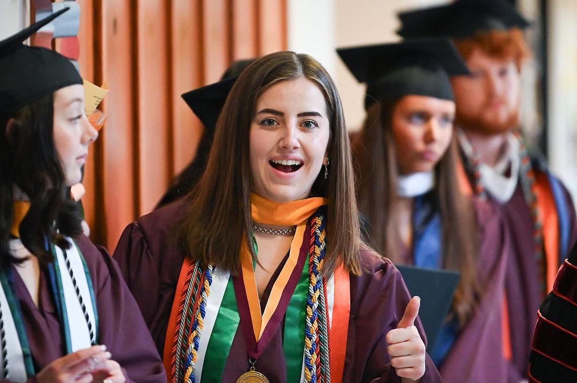 Image of mid-year graduates giving a 'thumbs up' to the photographer.